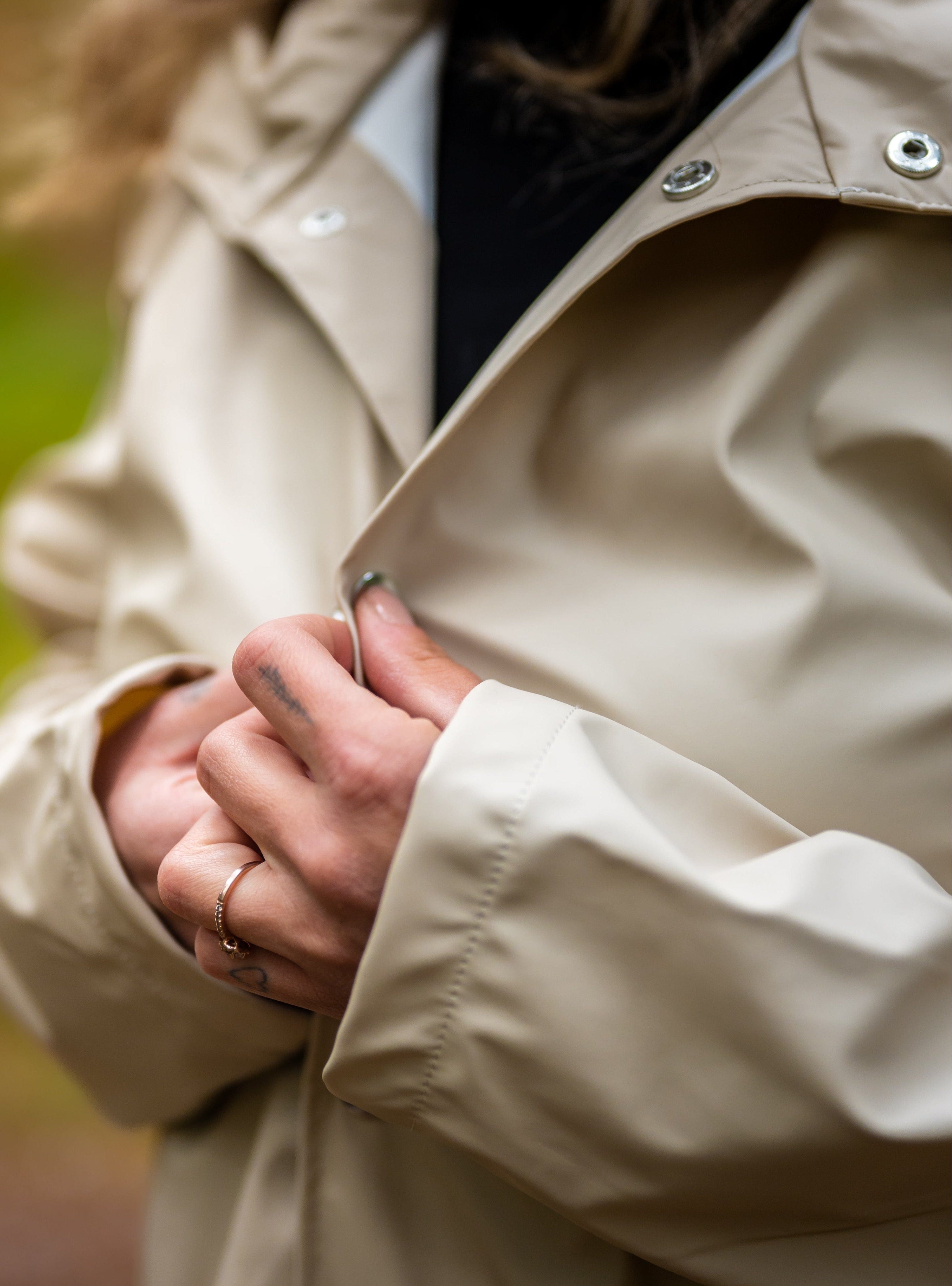 Close-up of a person wearing a beige jacket with a blurred natural background